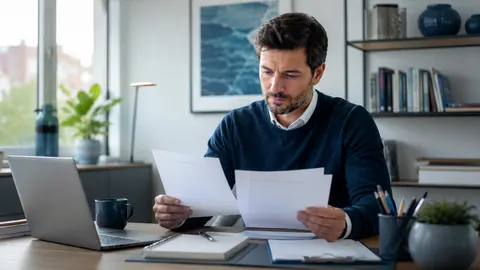 Berufstätige Person sitzt nachdenklich an einem modernen Arbeitsplatz und betrachtet Unterlagen zur finanziellen Planung.