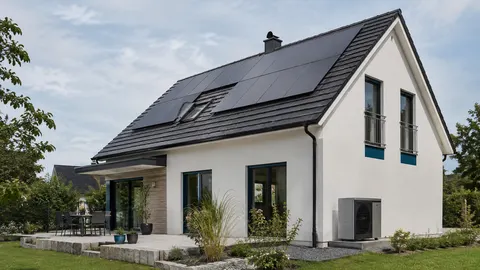 Modernes deutsches Einfamilienhaus mit Photovoltaikanlage auf dem Dach und realistisch installierter Wärmepumpen-Außeneinheit